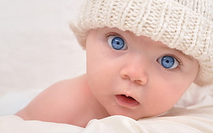 baby wearing white knit cap facing camera